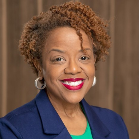 Sonya is a black woman with short auburn hair, bright lipstick, and a winning smile