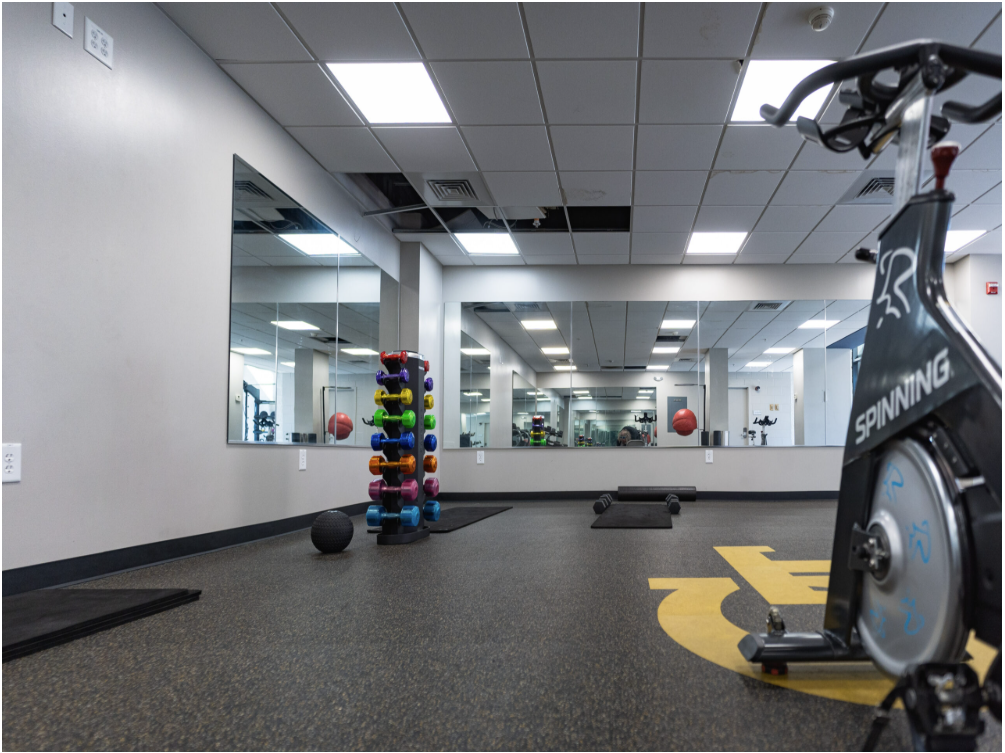 Woodruff North Gym with mirrors, a spin bike, and free weights.